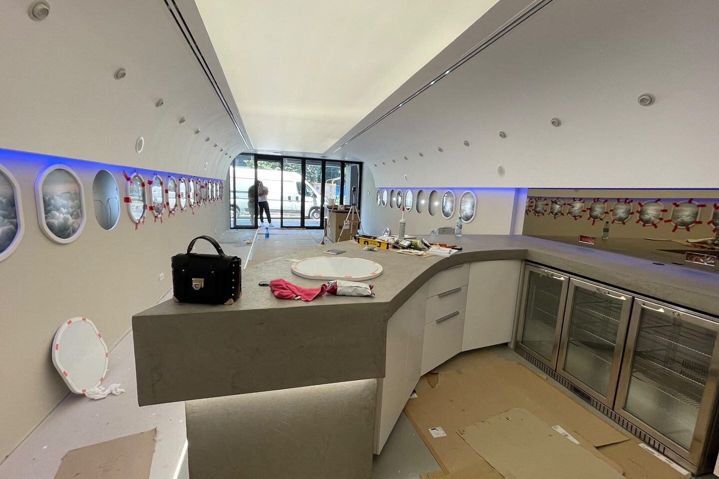 The bar counter under construction with glass-fronted fridges installed behind it and the floor still protected.