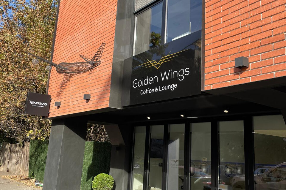 The street frontage: brick upper storey, dark ground floor with the café sign and full-height glazing.