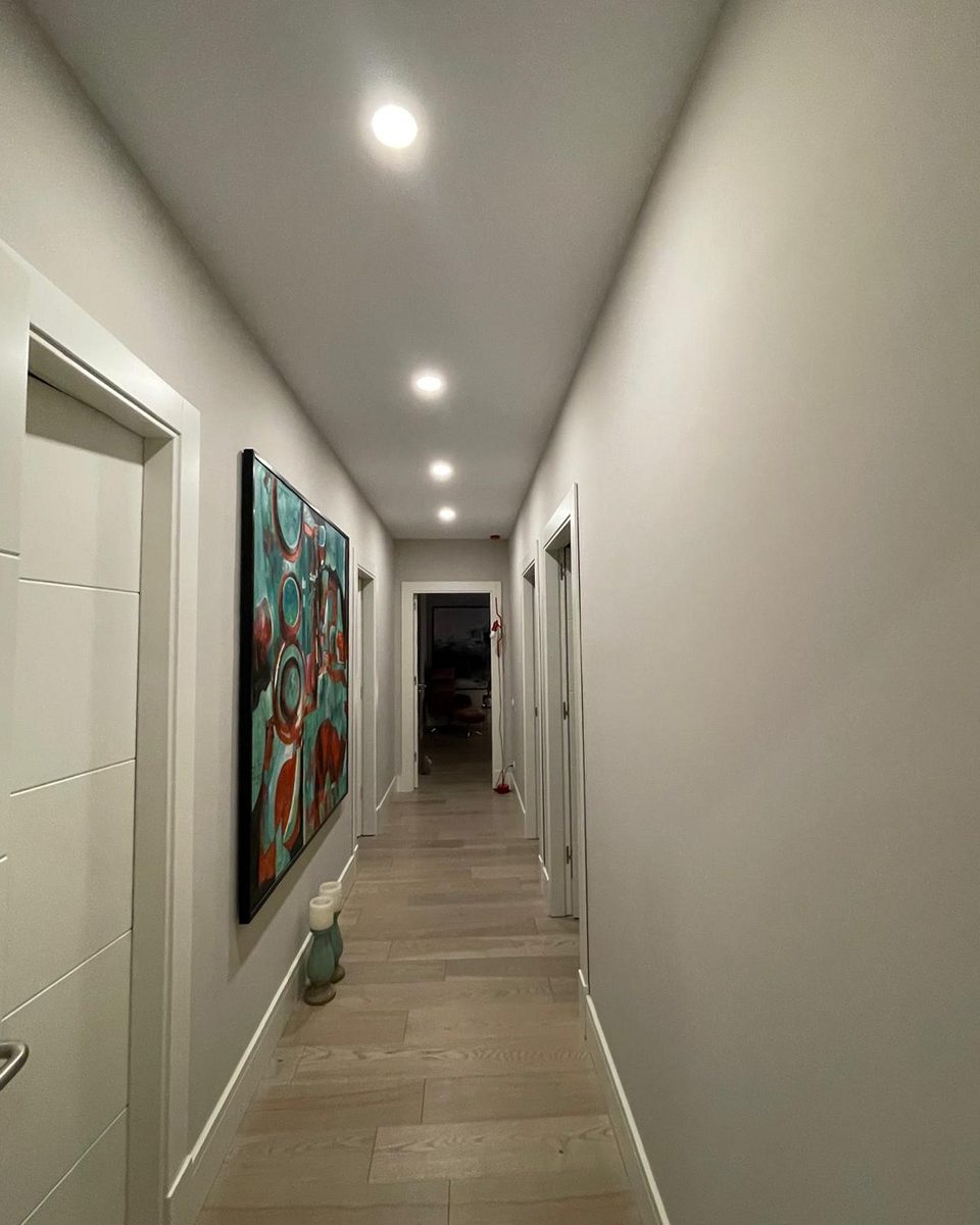 The hall: white doors and pale timber floor leading to a bright artwork at the end.
