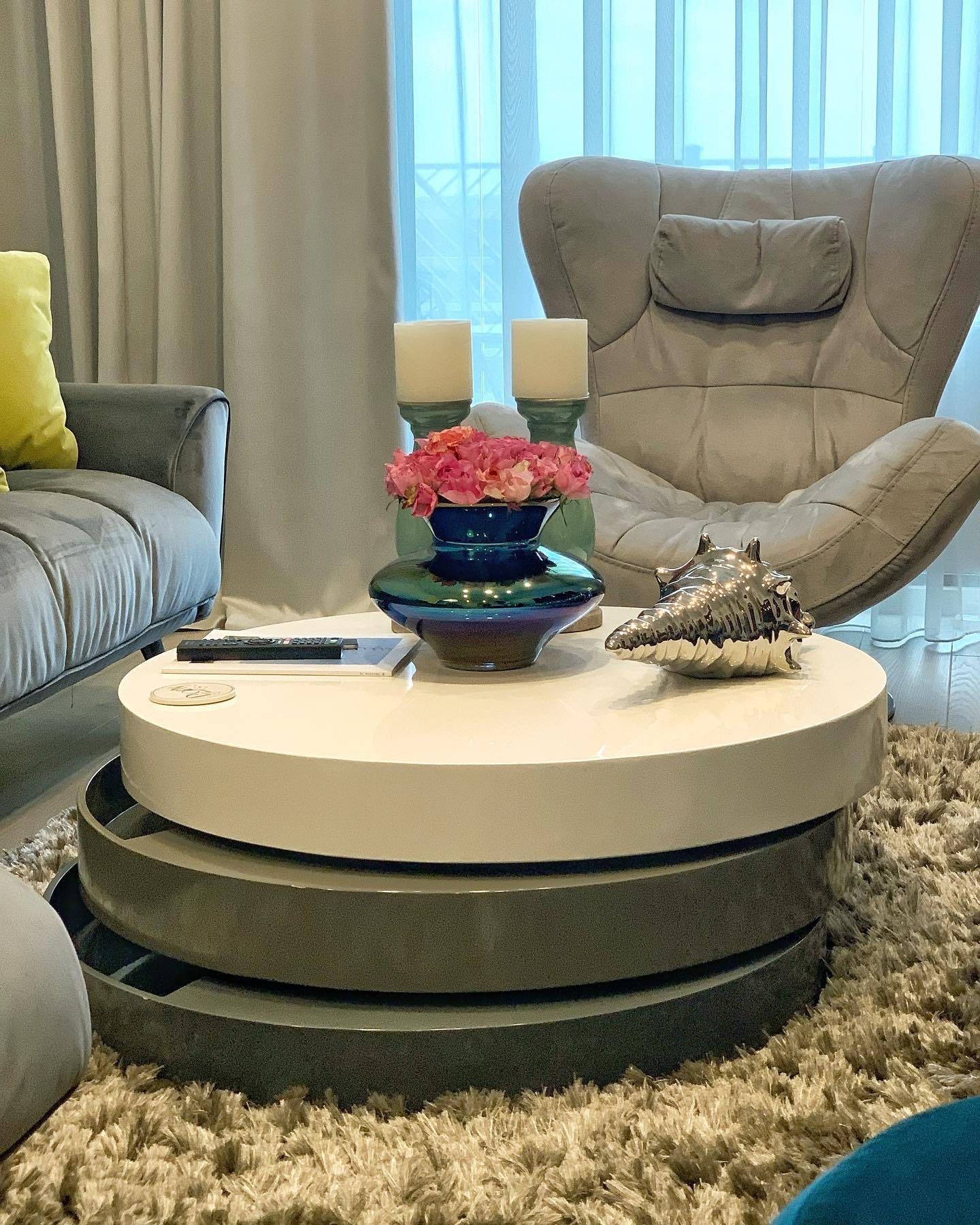 Living room detail: lacquered nesting tables on a shag rug in front of a grey armchair.