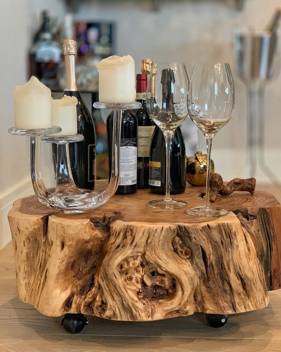 Detail: a solid timber slab table on castors dressed with wine and champagne glasses.