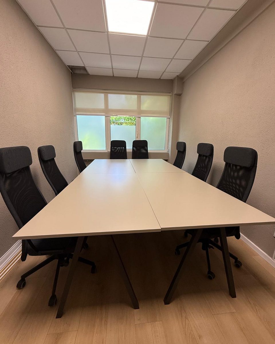 Boardroom: long light-oak meeting table with eight black mesh task chairs.